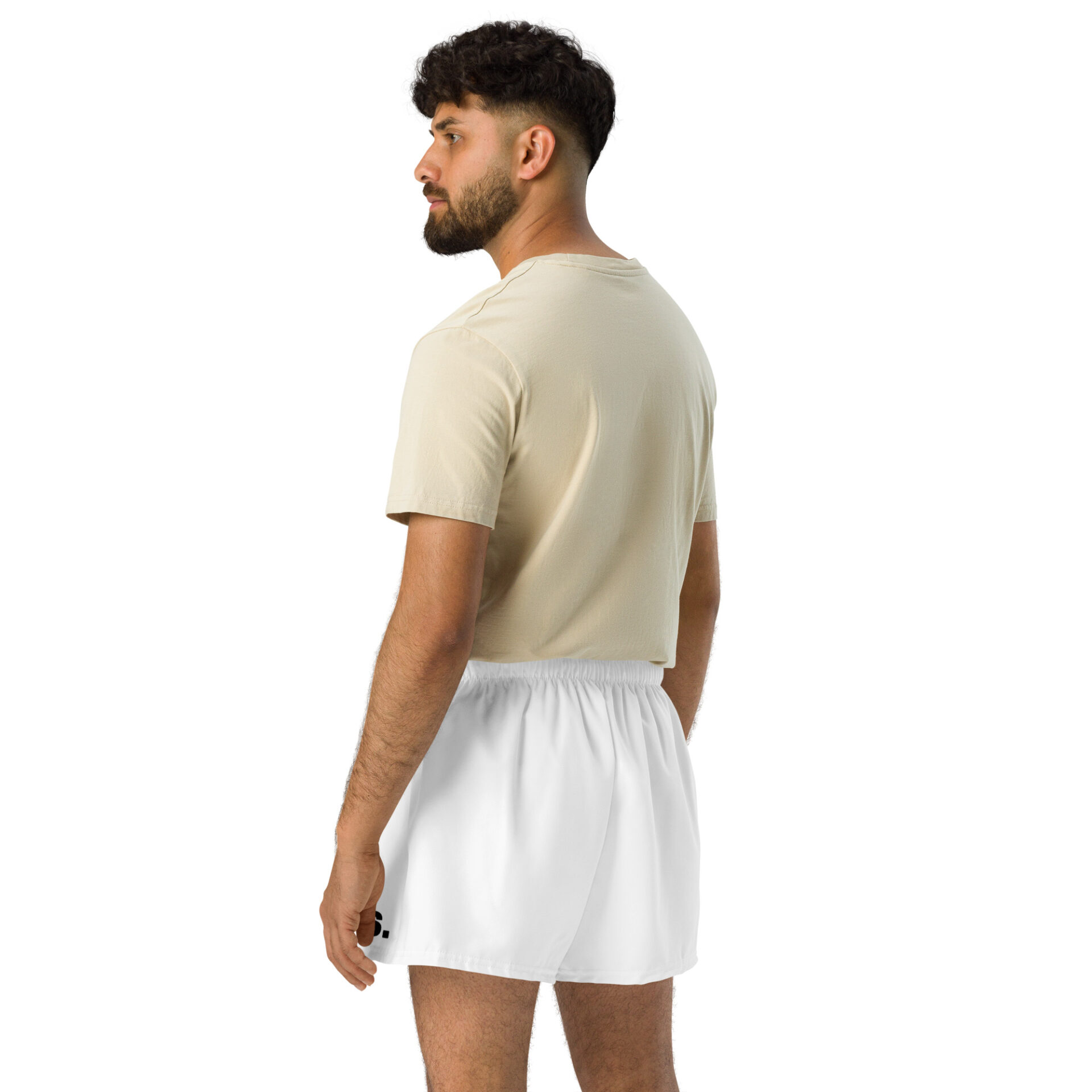 A man with short dark hair and a beard stands facing away, looking left. He sports a light beige t-shirt with BAAS Athletic Shorts in crisp white, capturing a casual sportswear vibe against the plain white background.