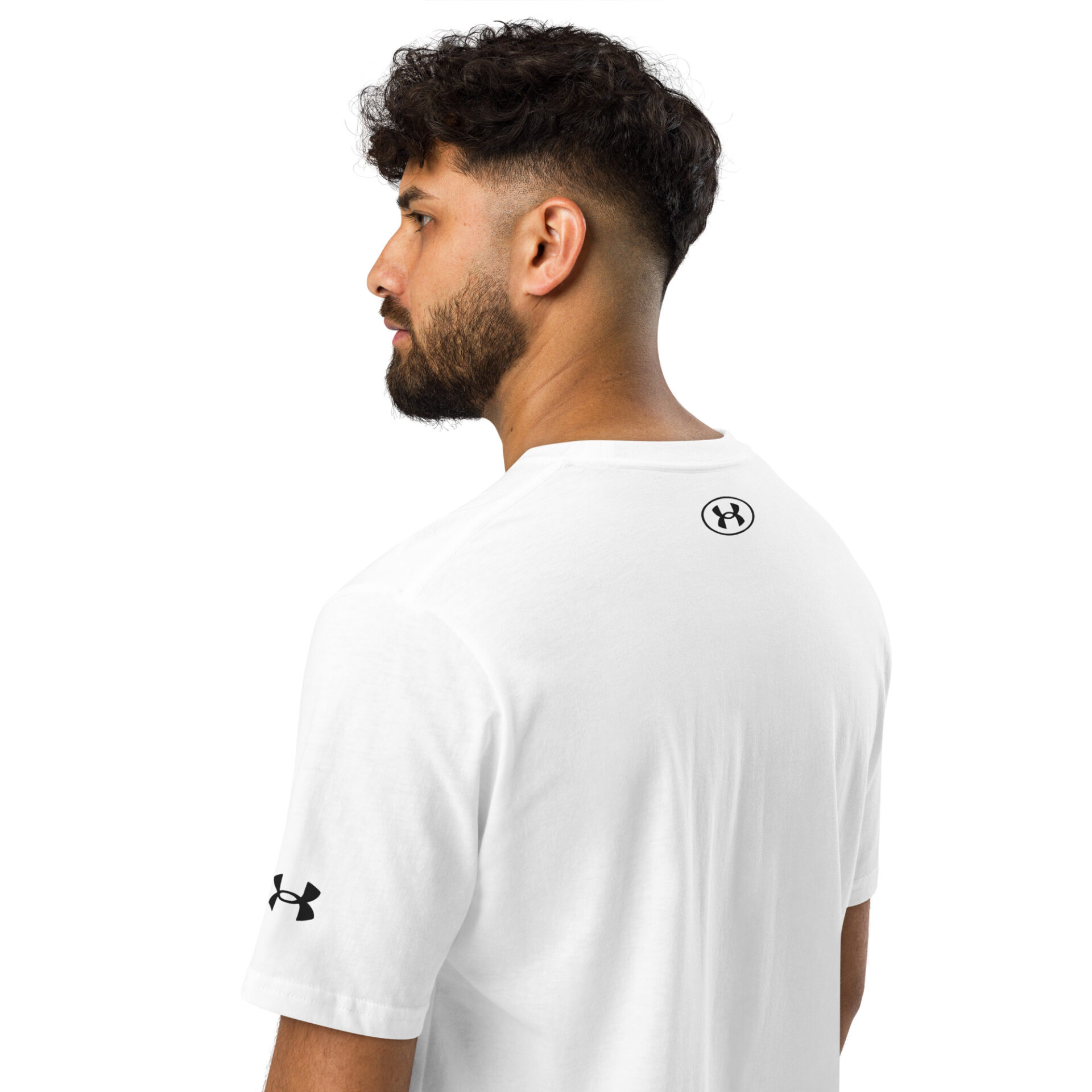A man with short, curly hair and a beard is seen from the back and side, wearing a white Under ArmourⓇ athletic t-shirt featuring the logo on the sleeve and below the neckline, set against a plain white background. A man with short, curly hair and a beard is seen from the back and side, wearing a white Under ArmourⓇ athletic t-shirt featuring the logo on the sleeve and below the neckline, set against a plain white background.