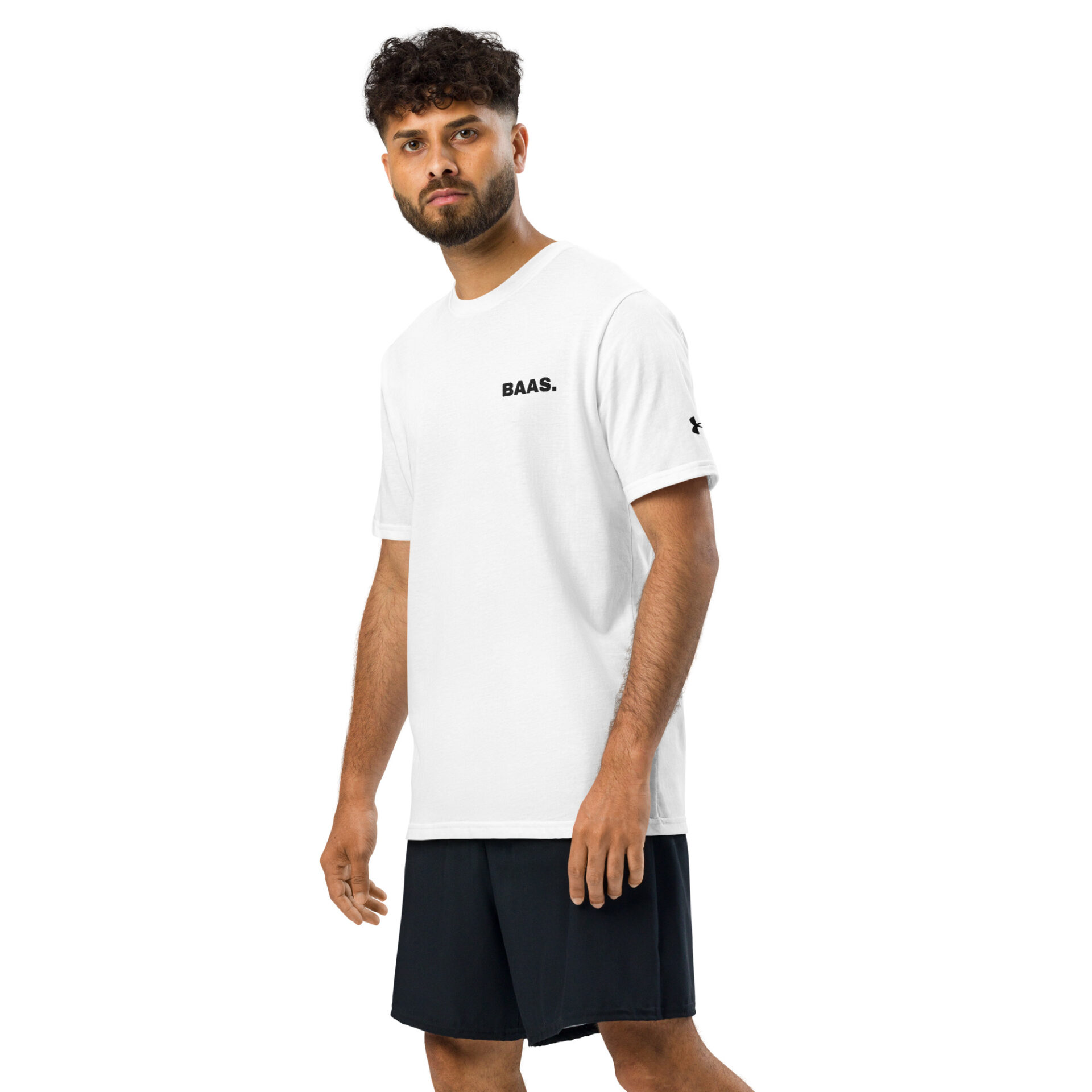 A man with curly hair and a beard wears a white Under ArmourⓇ athletic t-shirt with BAAS. printed on it and black shorts, standing against a plain white background. A man with curly hair and a beard wears a white Under ArmourⓇ athletic t-shirt with BAAS. printed on it and black shorts, standing against a plain white background.