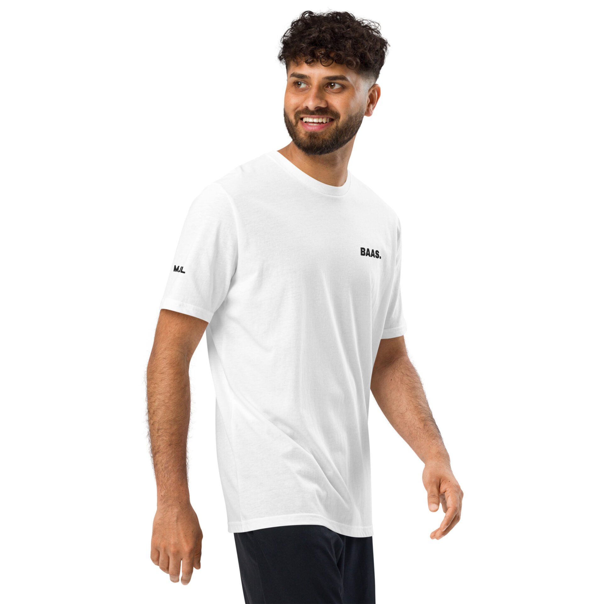 A man with curly hair and a beard smiles and looks to the side, wearing a plain white Under ArmourⓇ athletic t-shirt with small black text on the chest and sleeve, paired with black pants, standing against a white background. A man with curly hair and a beard smiles and looks to the side, wearing a plain white Under ArmourⓇ athletic t-shirt with small black text on the chest and sleeve, paired with black pants, standing against a white background.
