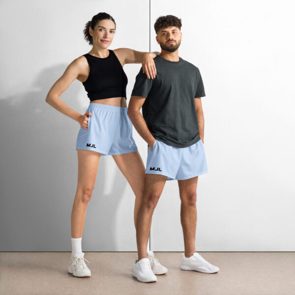 Two people stand side by side in MJL Athletic Shorts, white sneakers, and casual tops—a woman in a black crop top, a man in a dark gray t-shirt. The shorts display the signature MJL initials.