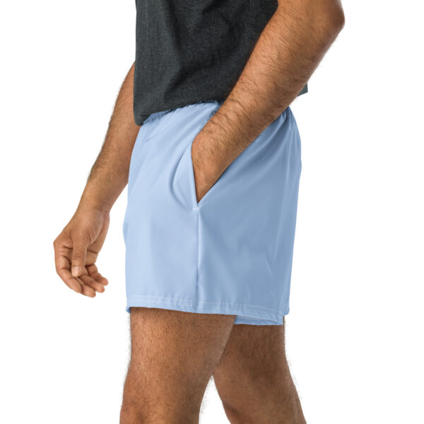 A person in a charcoal gray t-shirt and MJL Athletic Shorts, light blue, stands with hands in pocket; shown from shoulders to mid-thigh on a white background.