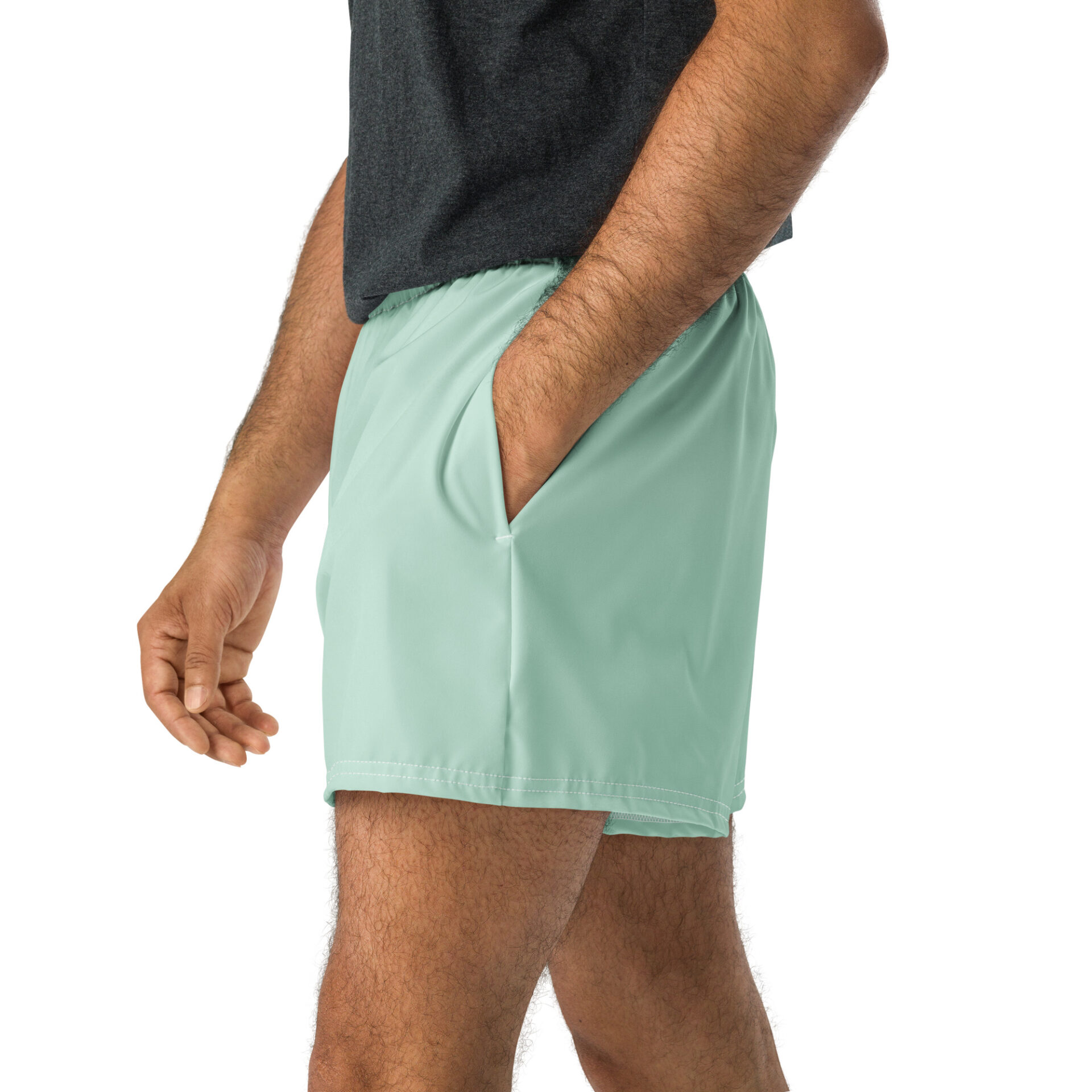 A person shown from the waist down against a white background wears light green MJL Athletic Shorts with one hand in the pocket and a dark grey shirt.