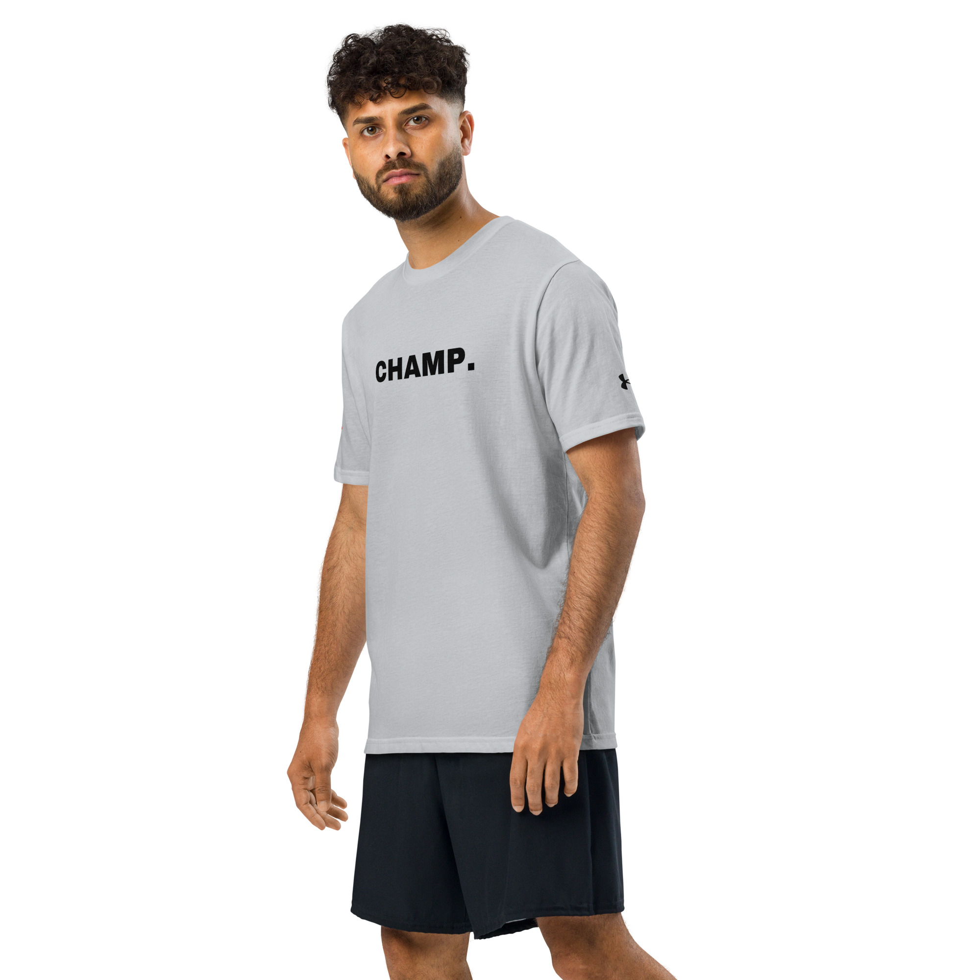 A man with short curly hair and a beard is wearing an Under ArmourⓇ athletic t-shirt embroidered with "CHAMP." on the front, paired with black shorts, standing against a plain white background. A man with short curly hair and a beard is wearing an Under ArmourⓇ athletic t-shirt embroidered with "CHAMP." on the front, paired with black shorts, standing against a plain white background.